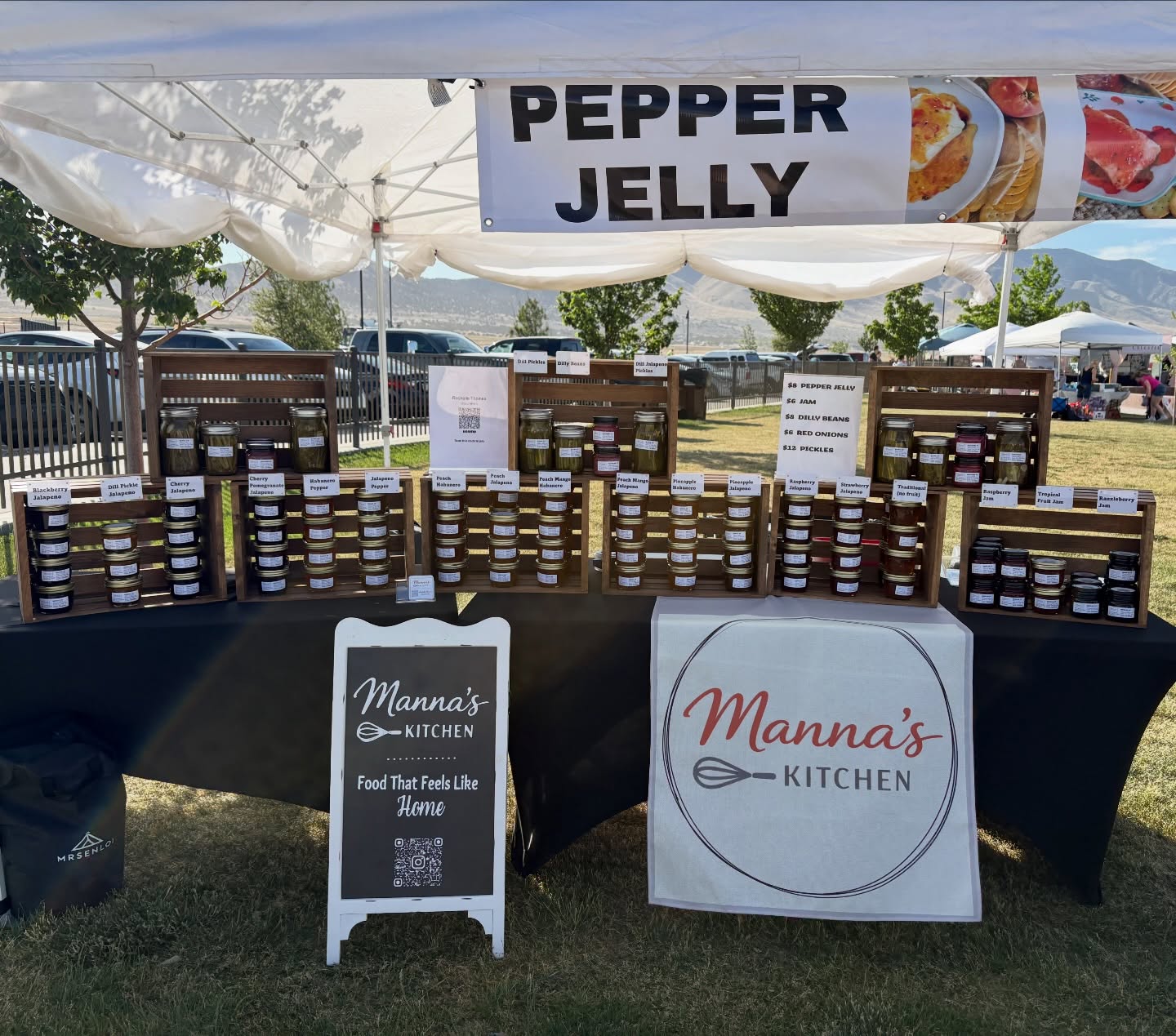Wooden racks of homemade pepper jelly jars at the farmer's market booth under a Pepper Jelly banner