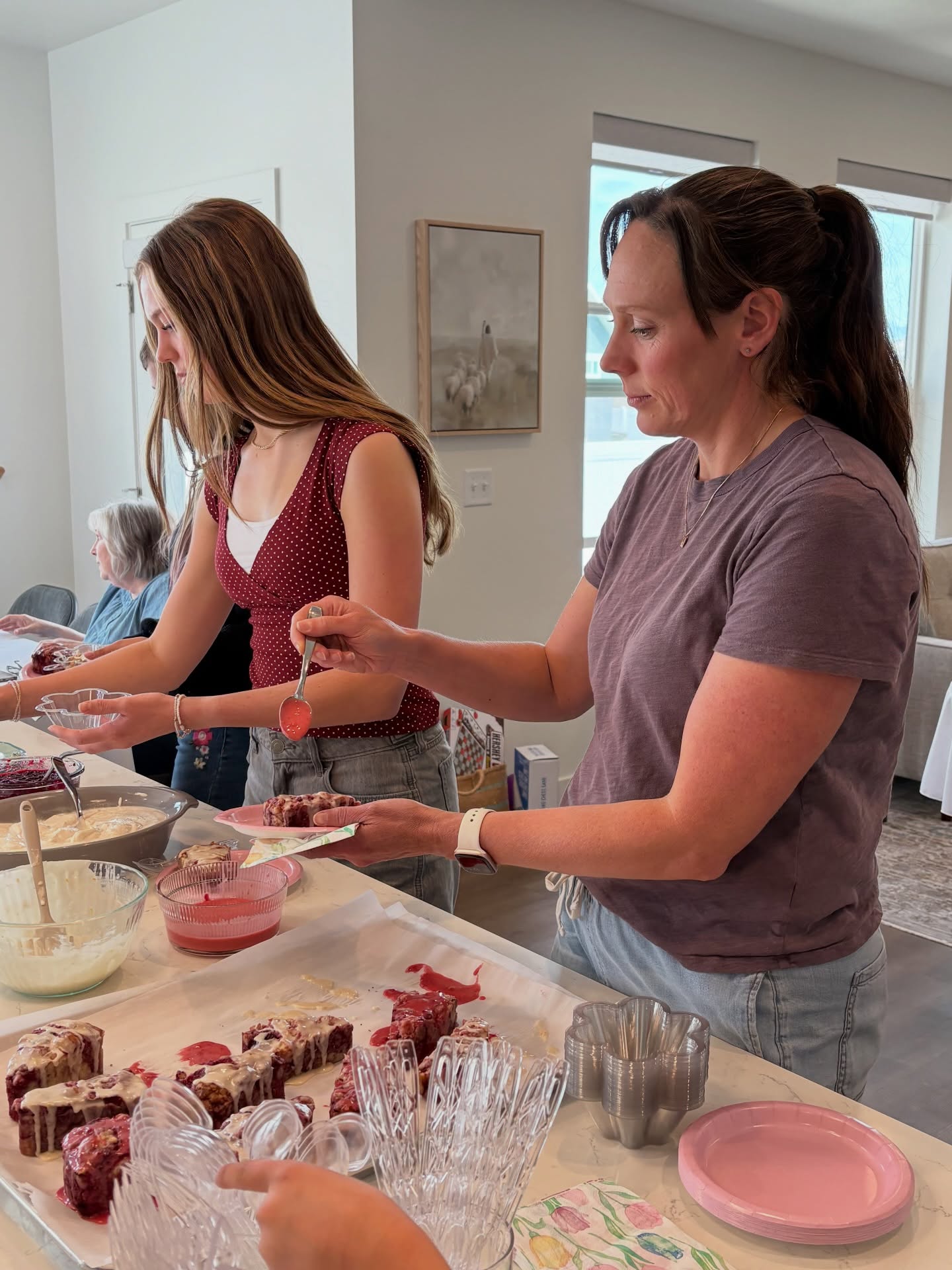 Women plating homemade scones and parfaits at a kitchen gathering